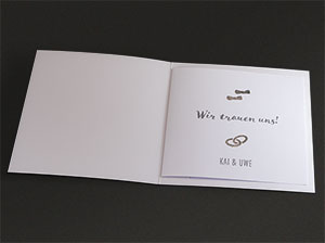 Vergrößerte Abbildung Liegende, aufgeklappte Einladungskarte mit eingestecktem, bedruckten Texteinleger.